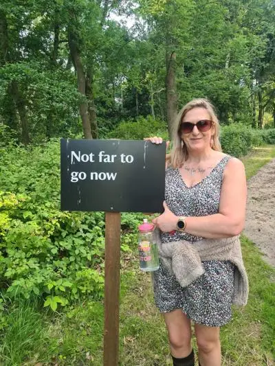 Melissa on her BPD recovery journey next to a sign saying "not far to go now."